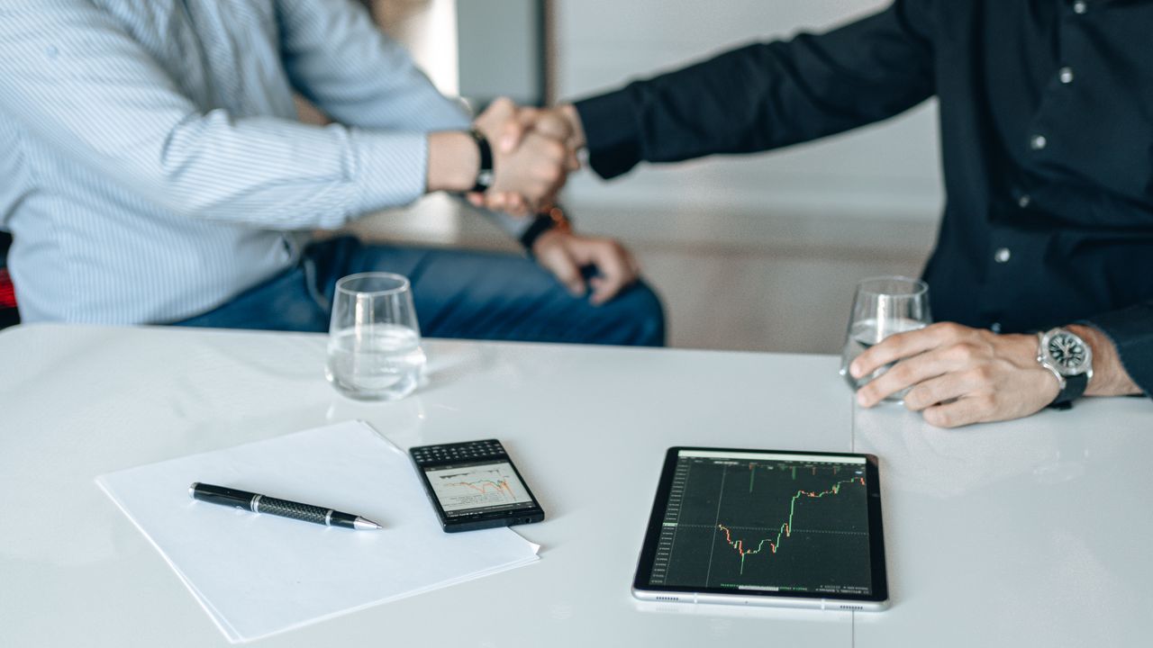 Crafting Captivating Headlines: Your awesome post title goes here Business meeting with handshake and financial analysis displayed on a tablet.